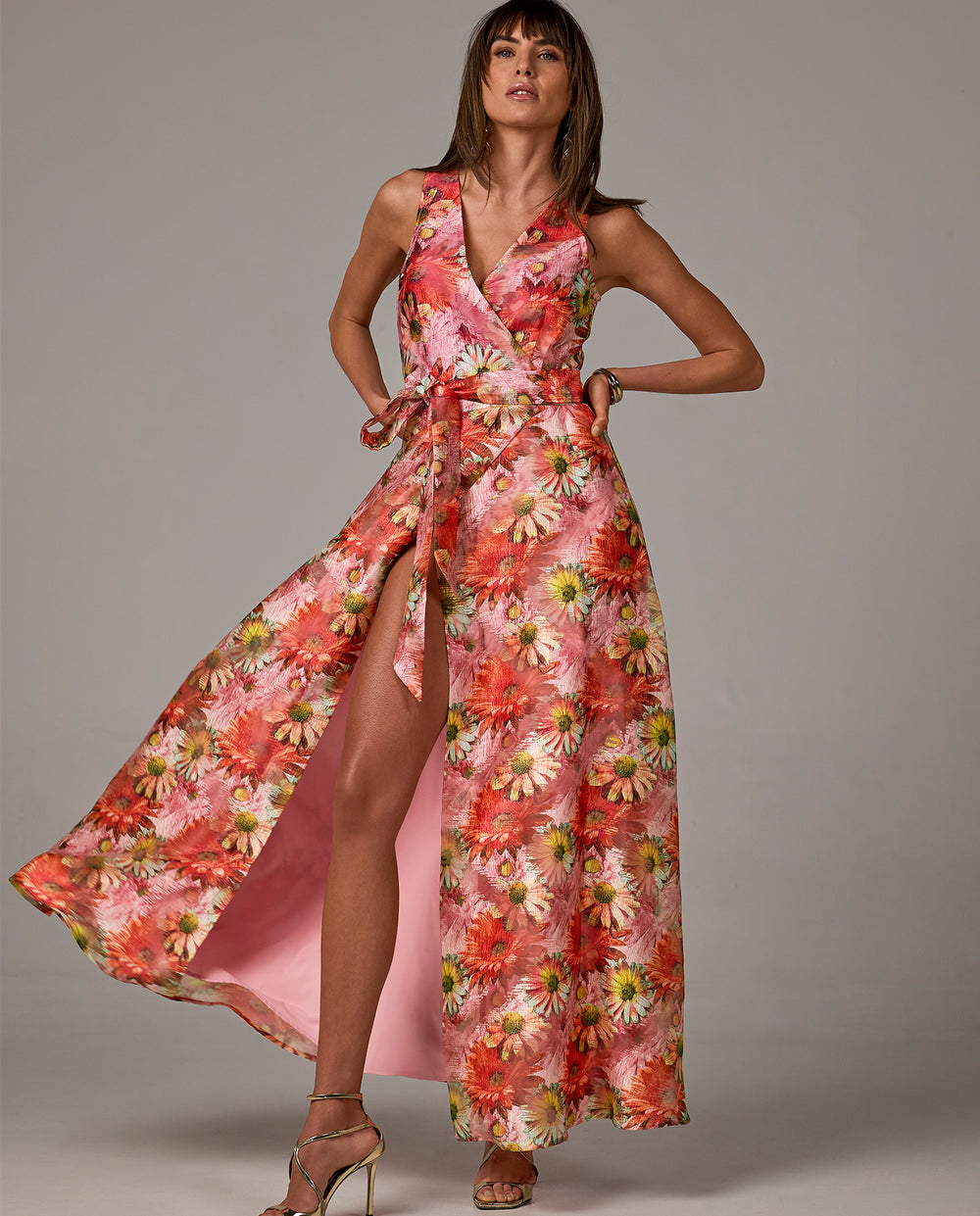 Model is wearing pink and red floral maxi dress with tie waist belt
